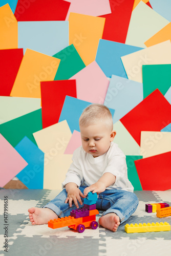 Obraz na płótnie A joyful toddler is fully engaged in imaginative play while building with colorful and vibrant blocks inside a brightly decorated room, demonstrating creativity and fun in their playful environment w salonie