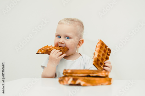 Obraz na płótnie A cheerful child joyfully enjoys waffles, creating happy memories with family. This scene captures a grinning child celebrating the simple joys of food, surrounded by love and laughter w salonie