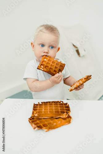 Obraz na płótnie A cute little toddler is having a wonderful time enjoying some delicious waffles in a beautifully minimalistic setting that enhances the overall experience, bringing joy to breakfast time w salonie