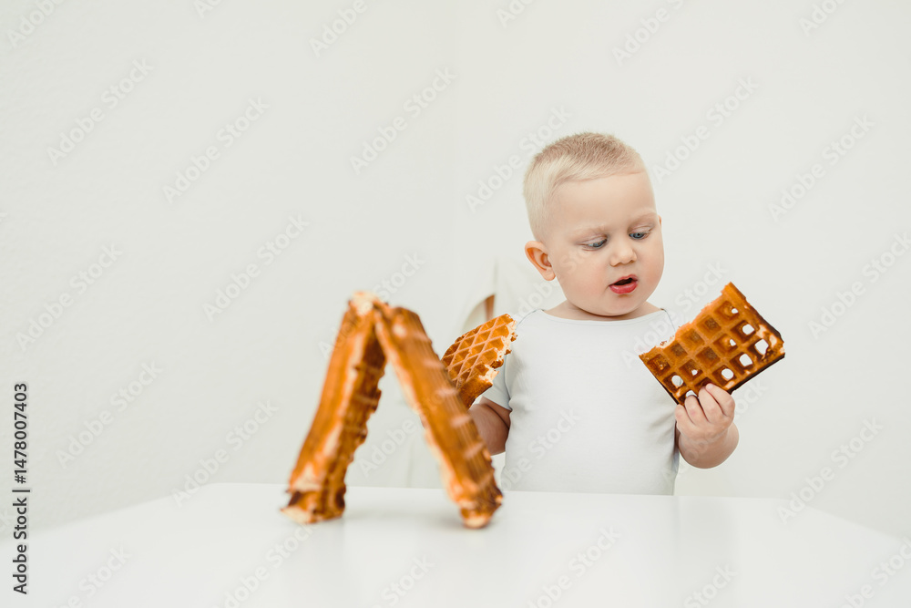 In a bright, minimalistic setting, a curious toddler joyfully explores delightful waffle shapes, showcasing their enthusiasm and excitement during this whimsical culinary adventure