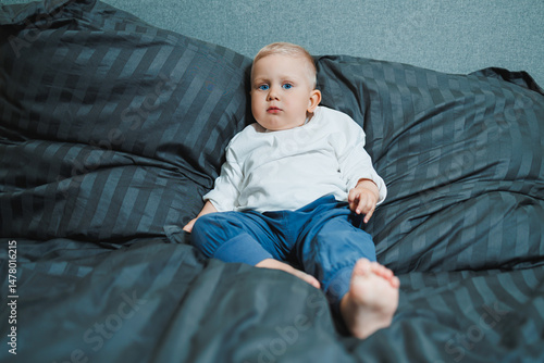 Obraz na płótnie An adorable baby relaxes peacefully on a cozy bed with plush bedding in a beautifully designed modern room, capturing the true essence of childhood happiness, warmth, comfort, and joy w salonie