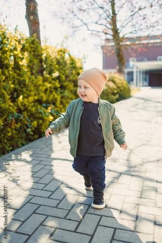 Obraz na płótnie A joyful child dressed in a casual, comfortable outfit is delighting in a sunny day outdoors, soaking up the surroundings and embracing the beauty of nature with happiness all around them w salonie
