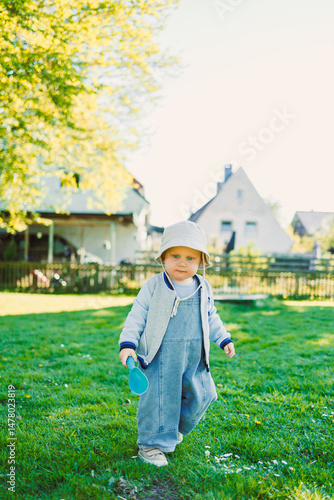 Obraz na płótnie A charming child is enjoying a pleasant and sunny day outdoors, surrounded by a lush green landscape that enhances their joy and innocence as they explore their beautiful and vibrant environment w salonie