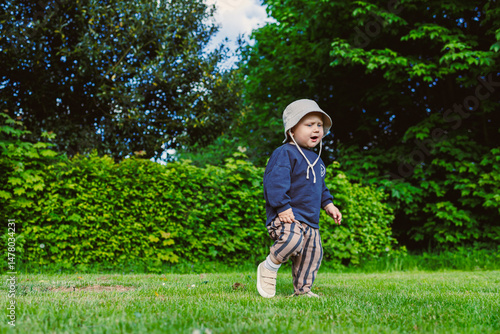 A curious toddler, filled with excitement and energy, is happily exploring the wonders of nature on a beautiful sunny day in a vibrant green park, surrounded by the joys of the outdoors