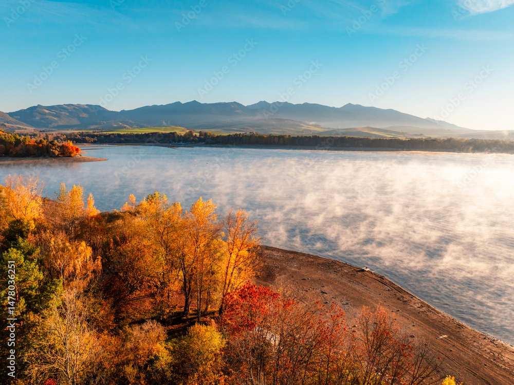Liptov region with Tatras mountains around. Liptovska mara dam landspace. Autumn deciduous forest view from above