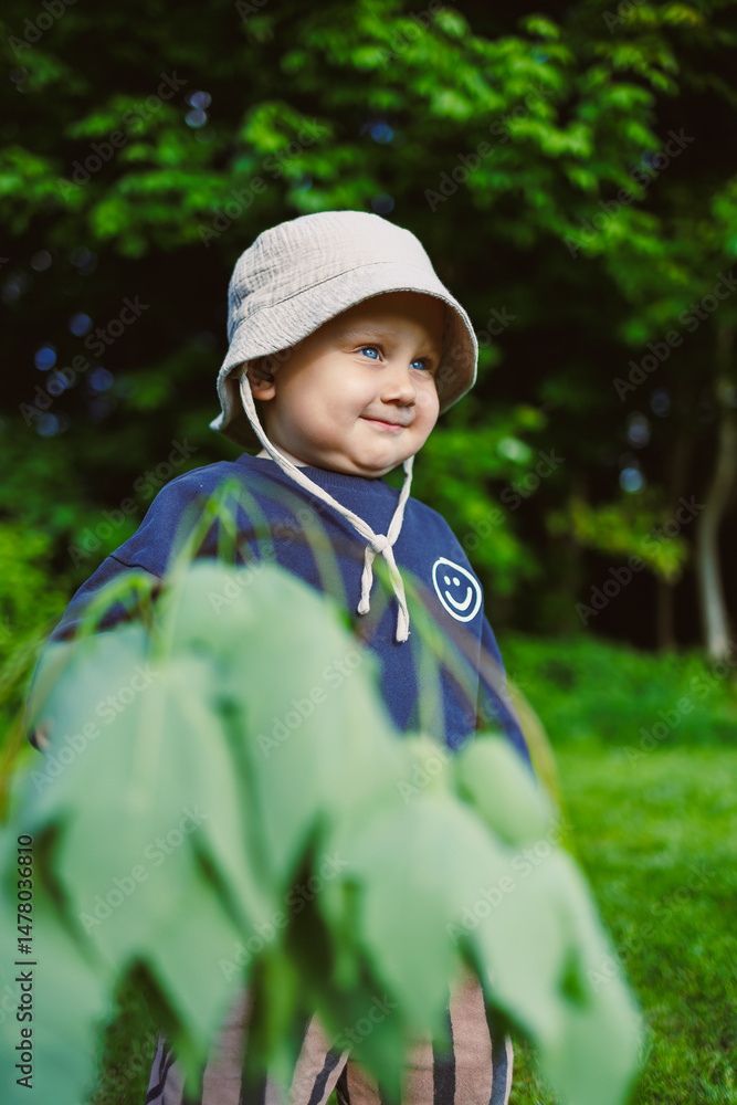 A joyful child happily exploring the wonders of nature in a lush, vibrant green garden, adorned with greenery, wearing a casual outfit, and exuding a cheerful smile that reflects pure happiness