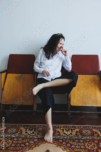 Obraz na płótnie Charming and Joyful Young Woman Laughing Cheerfully in a Relaxed and Casual Outfit An Enchanting Indoor Portrait Surrounded by Vintage Chairs, Highlighting Her Playful and Happy Spirit Beautifully w salonie