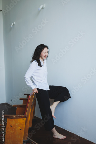 Obraz na płótnie An elegant woman is playfully posing within a beautifully minimalist interior setting, exuding charm and confidence as she embraces her individuality and expresses her fashionable style w salonie