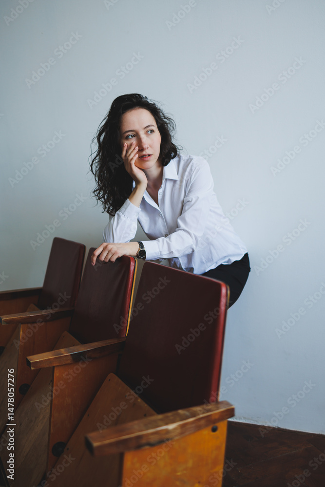 In a stylish studio, a young woman showcases her fashion sense in a chic white shirt, posing by a vintage bench that blends modern and classic elements, creating an inspiring atmosphere