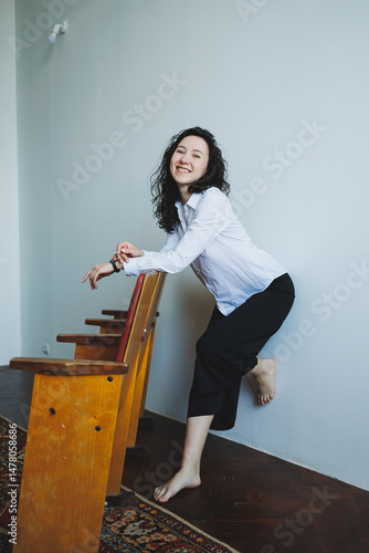 Obraz na płótnie In a beautifully colorful and artistic space, a cheerful young woman joyfully plays on vibrant, uniquely designed chairs, fully embodying creativity and a dynamic, positive, energetic lifestyle w salonie