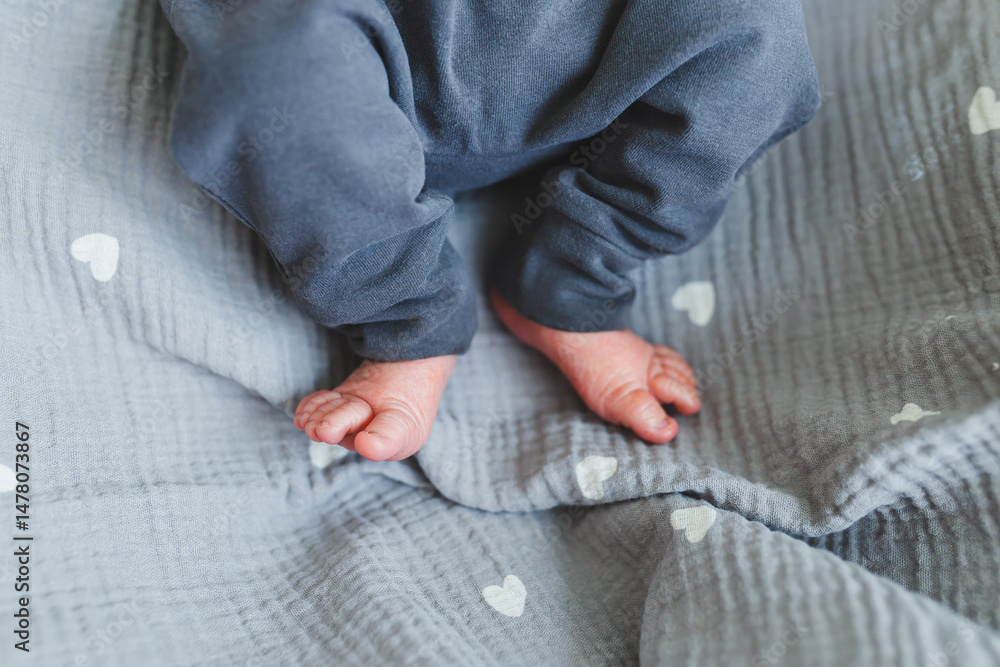 Adorable and delightful baby feet resting on a soft, plush gray blanket that features lovely heart patterns, capturing the essence of childhood and the innocence of early life experiences
