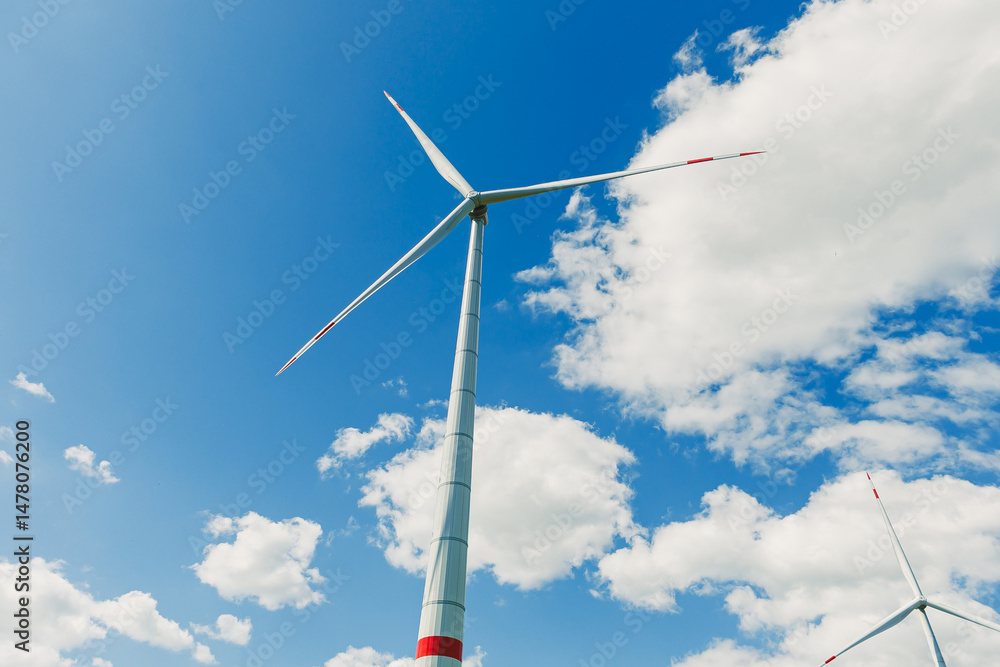 Vibrant wind turbines shine against a blue sky with white clouds, showcasing clean energys beauty and emphasizing sustainabilitys importance for agriculture and environmental health