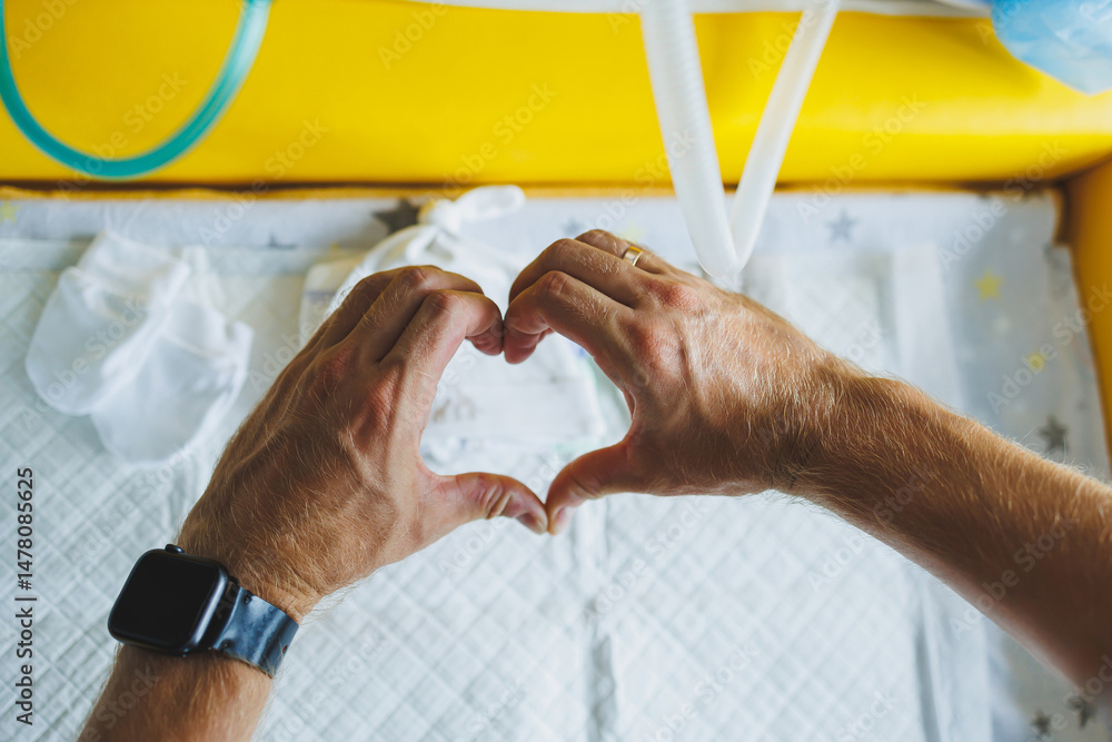 In a cozy setting, hands form a heart shape above a babys crib, symbolizing the deep love and connection that binds a family as they cherish their precious newborn with joy and tenderness
