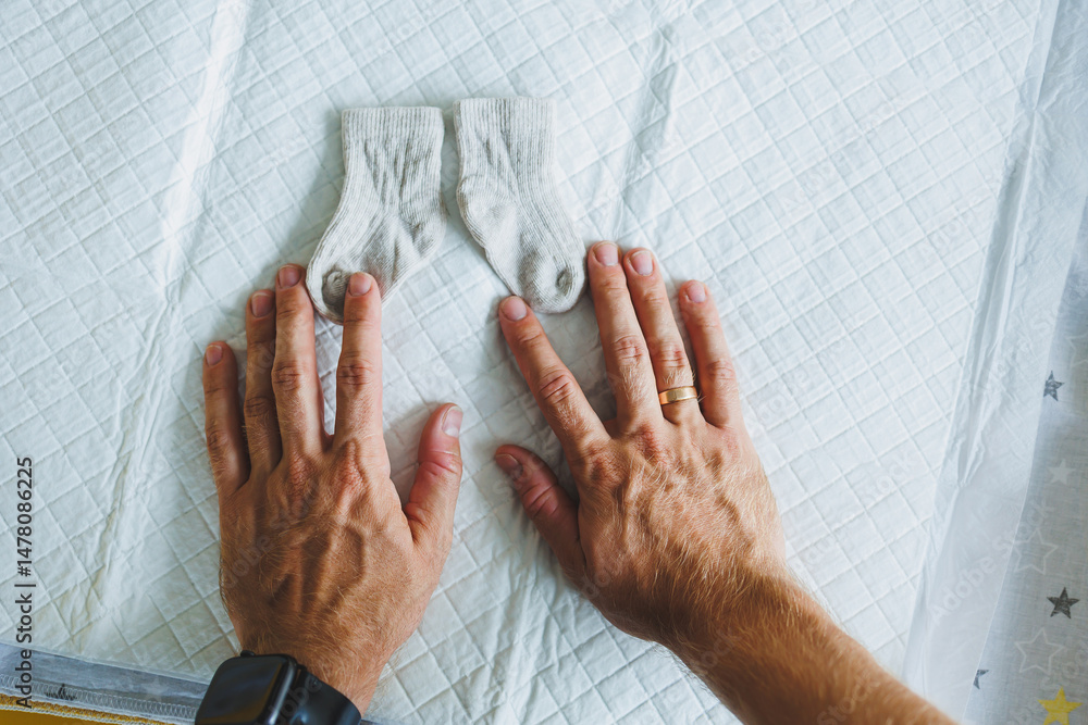 Tender Moments In a tranquil and serene environment, a new parents gentle hands tenderly cuddle and lovingly cradle precious baby booties, radiating excitement and love for their newborn child