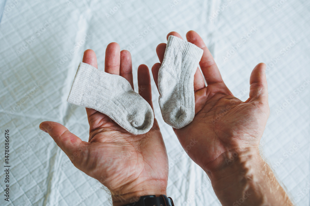 A Tender Moment Gently Comparing Adorable Baby Socks in Their Hands This Beautiful Scene Symbolizes the Start of New Parenthood Filled with Joyful Anticipation and Loving Emotions