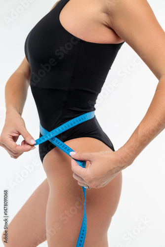 Beautiful fitness woman. Sporty girl measuring her waist. On white background