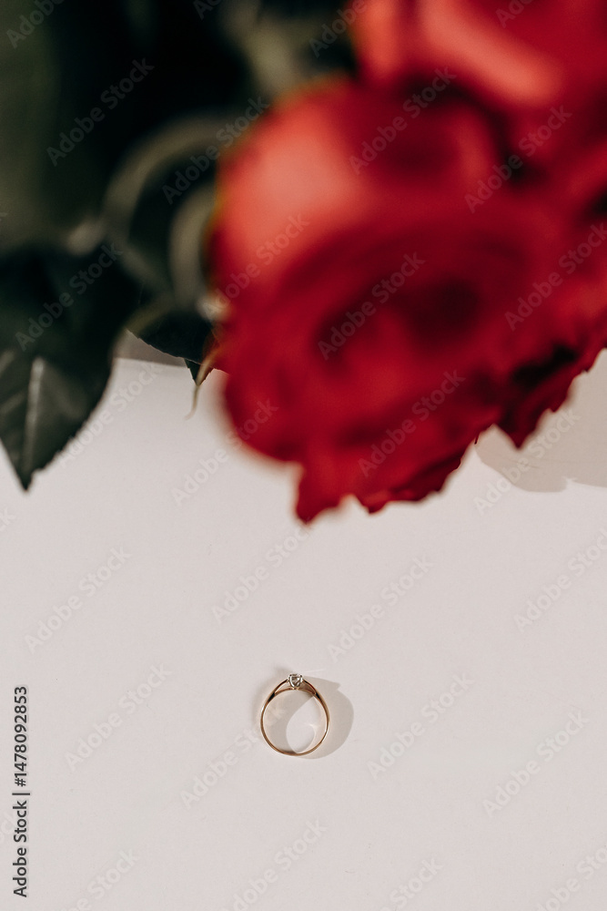 The stunning golden ring is beautifully surrounded by elegant red roses, which together symbolize love and unwavering commitment between partners in a relationship that lasts a lifetime