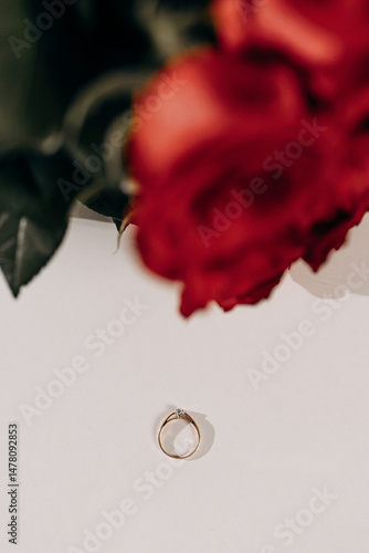 Obraz na płótnie The stunning golden ring is beautifully surrounded by elegant red roses, which together symbolize love and unwavering commitment between partners in a relationship that lasts a lifetime w salonie