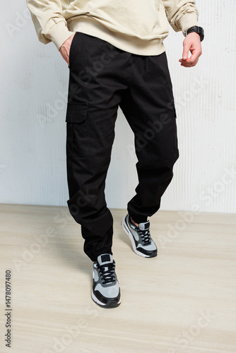 Obraz na płótnie Explore the latest collection of trendy black cargo pants that are perfectly matched with stylish sneakers, making them ideal for a modern casual look that truly stands out in todays fashion scene w salonie