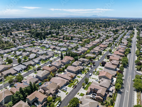 Aerial view of a suburban residential neighborhood in Stockton, California, showcasing rows of single-family homes, streets, and surrounding farmland. Ideal for topics related to urban planning, Calif