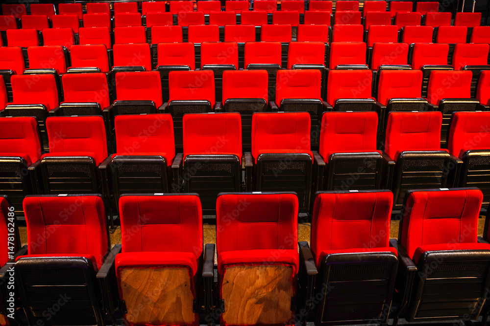 Fototapeta premium Rows of red seats in an auditorium or cinema hall. Evokes entertainment, leisure, and culture.