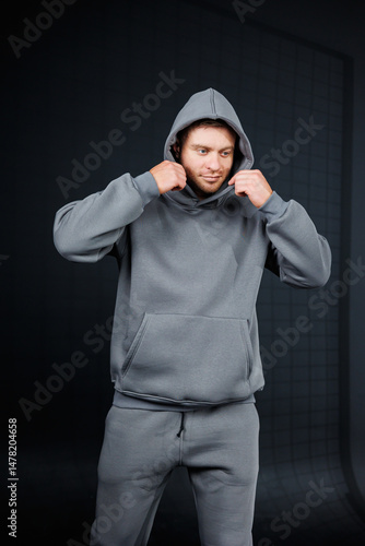 Stylish Athletic Wear A man is sporting a fashionable gray hoodie paired with joggers, captured in a dynamic pose that showcases his active lifestyle and love for athletic fashion