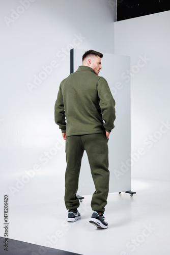 A fashionable and stylish male model is wearing an olive green tracksuit, effectively showcasing the latest modern athleisure fashion trends through a vibrant and dynamic pose that captures attention