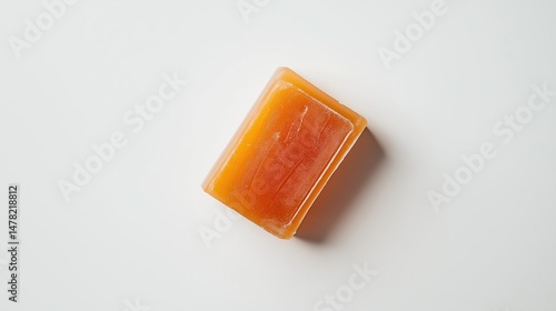 A close up studio shot of an orange glycerin soap bar on white