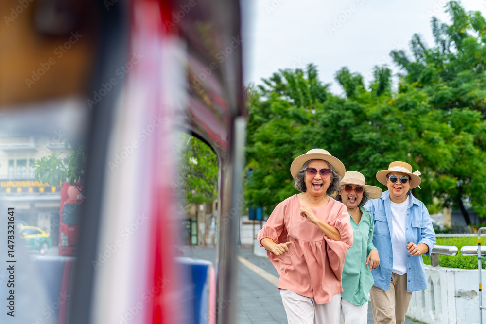 Obraz premium Happy Asian senior woman tourist travel Bangkok city, Thailand on summer holiday vacation. Elderly women friends enjoy outdoor lifestyle travel in the city by three wheeled vehicles Tuk Tuk taxi.