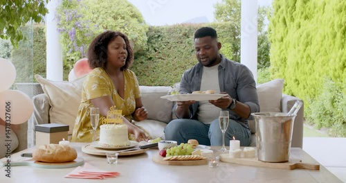Celebrating birthday with cake, African American couple having conversation outdoors