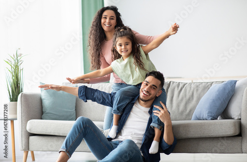 Portrait Of Happy Middle Eastern Parents Bonding With Their Child At Home, Happy Arab Family With Daughter Having Fun In Living Room, Playing And Laughing, Enjoying Spending Time Together, Free Space