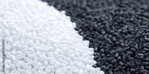 White and black plastic granules are spread in a divided pattern on a surface. Concept: industrial materials, contrast, plastic production