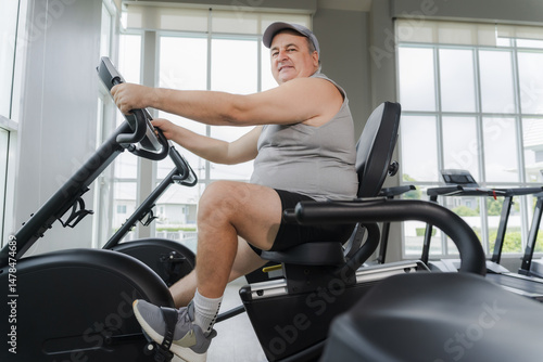 A middle-aged, overweight man uses a bicycle to exercise at the gym.
