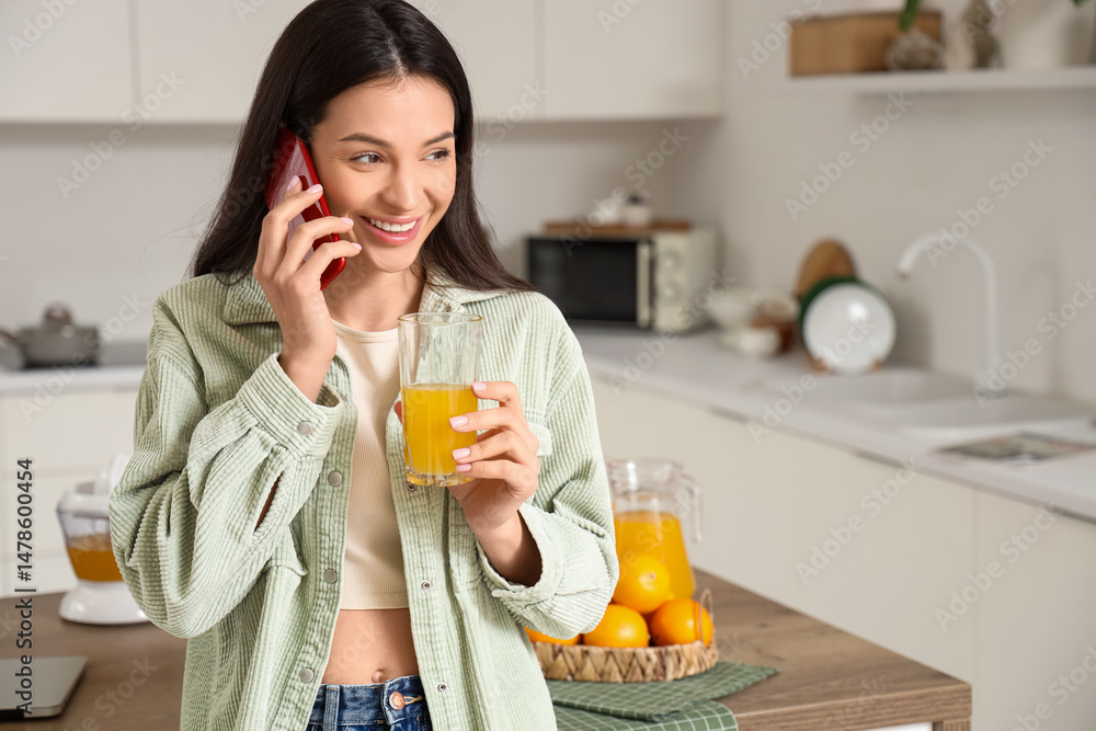 Young woman with sweet orange juice talking by phone in kitchen Young woman with sweet orange juice talking by phone in kitchen