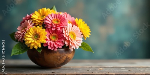 Wallpaper Mural A vibrant bouquet of pink and yellow gerbera daisies arranged in a rustic wooden bowl, sitting on a weathered wooden surface against a blurred teal background Torontodigital.ca