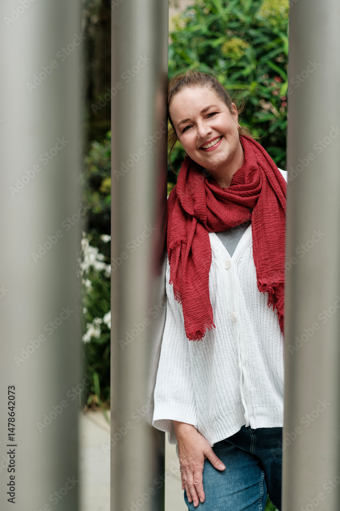 Smiling woman leaning against metal poles in urban setting Smiling woman leaning against metal poles in urban setting