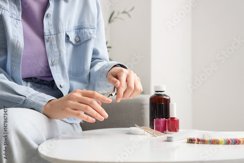 Young woman doing manicure ...