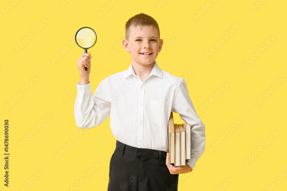 Cute little boy with magnifier and books on color background Cute little boy with magnifier and books on color background