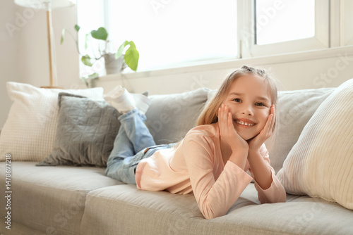 Little girl lying on sofa a...