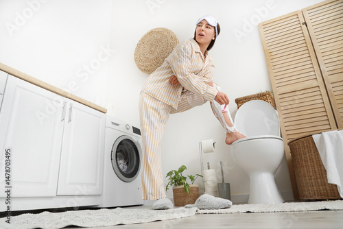 Young woman shaving leg in ...