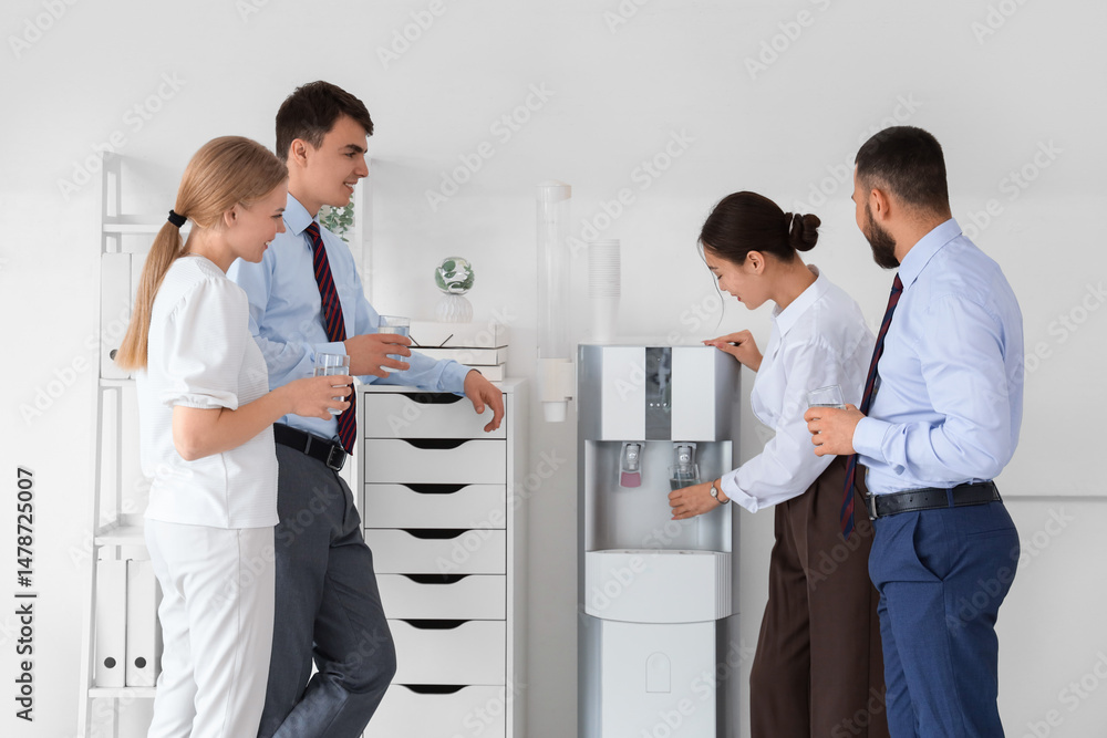 Obraz premium Group of business people pouring water from cooler in office