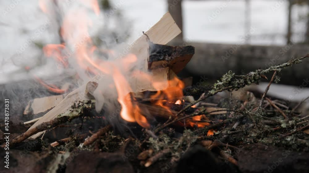 Man putting firewood on campfire, slow motion, close-up Man putting firewood on campfire, slow motion, close-up