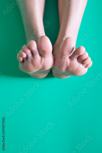 Feet of a young woman on a green background,