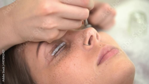 The master laminates the eyelashes of a young beautiful girl. 4K close-up