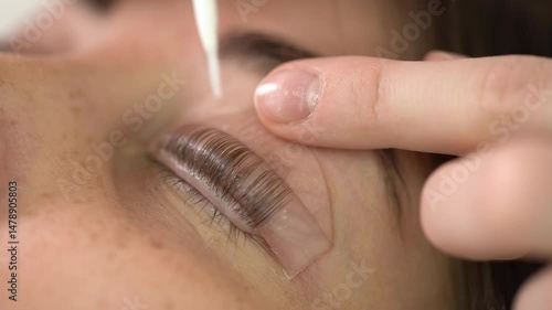 The master laminates the eyelashes of a young beautiful girl. 4K close-up