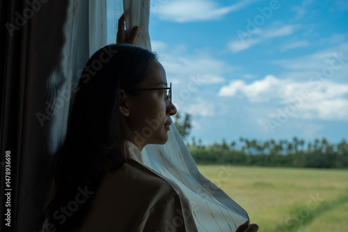 The housekeeper is arranging the curtains and cleaning the windows of the resort bedroom