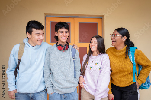 Latino high school students laughing together in front of school building