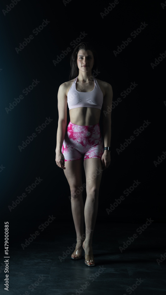 Obraz premium Young beautiful woman with athletic body on dark background. Fitness girl 