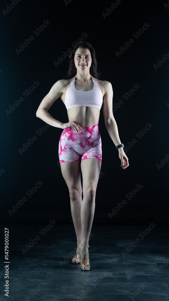 Fototapeta premium Young beautiful woman with athletic body on dark background. Fitness girl 