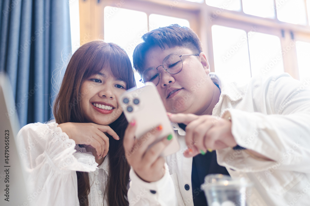 Diverse couple of gender expressions enjoy lifestyle moments together using smartphone in cozy indoor setting with natural light and smiles Diverse couple of gender expressions enjoy lifestyle moments together using smartphone in cozy indoor setting with natural light and smiles